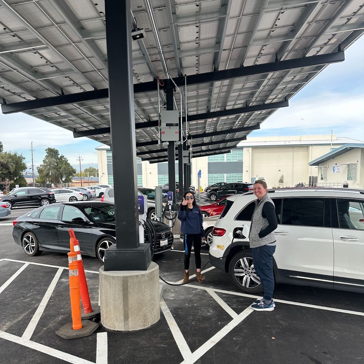 People standing in a parking lot underneath solar panels
